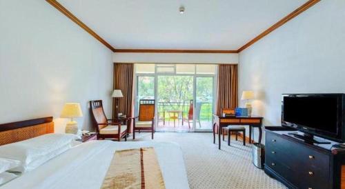 a bedroom with a bed and a tv and a desk at Kunming Dianchi Garden Hotel & Spa in Kunming