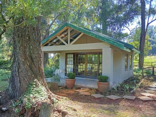 a small house with a tree in front of it at The Retreat Country Lodge in Romelcoh