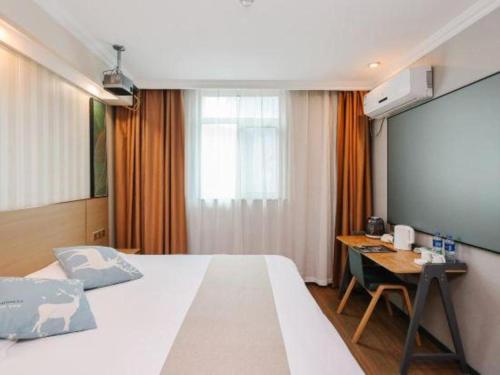 a bedroom with a bed and a desk and a screen at GreenTree Inn Zhenjiang Center Street No.1 Peoples Hospital Express Hotel in Zhenjiang
