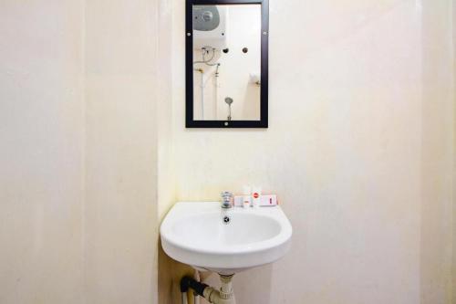 a bathroom with a white sink and a mirror at Super OYO 1788 House 24 in Yogyakarta