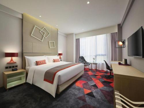 a hotel room with a large bed and a television at Q Hotel Shanghai Pudong in Shanghai