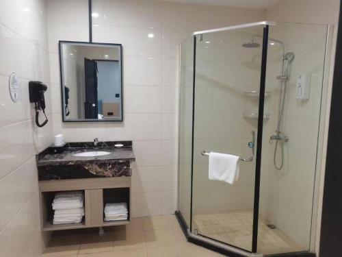 une salle de bain avec une douche en verre et un lavabo dans l'établissement GreenTree Inn Anqing Tongcheng South Shengtang Road Shengtang International Business Hotel, à Wangguolu