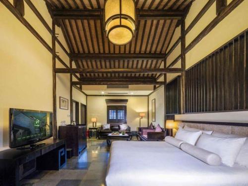 a bedroom with a large white bed and a tv at Hotel Dayu Kaiyuan in Shaoxing