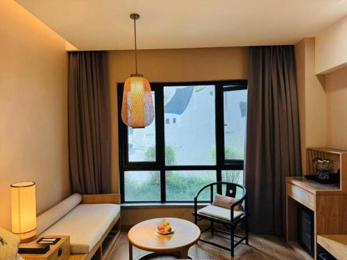 a living room with a couch and a large window at Hotel Dayu Kaiyuan in Shaoxing