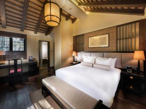 a bedroom with a large white bed and a desk at Hotel Dayu Kaiyuan in Shaoxing