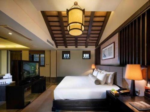 a bedroom with a large bed and a television at Hotel Dayu Kaiyuan in Shaoxing