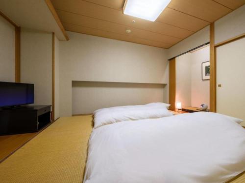 a bedroom with a bed and a flat screen tv at Grand Hotel New Oji in Tomakomai