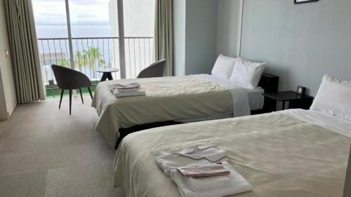 a hotel room with two beds and a balcony at Hamakan Hotel in Unzen
