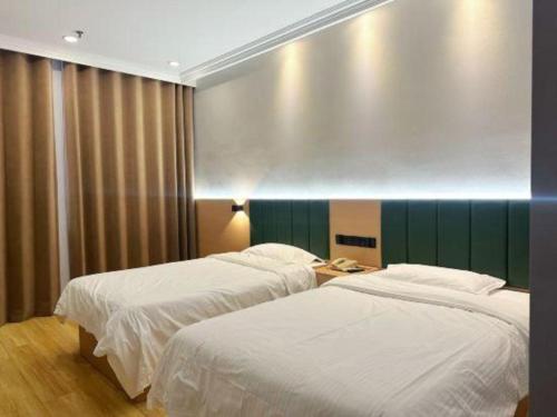 a bedroom with two beds and a green wall at GreenTree Inn Jiangsu Suqian Yiwu Business Center Fukang Avenue Express Hotel in Suqian