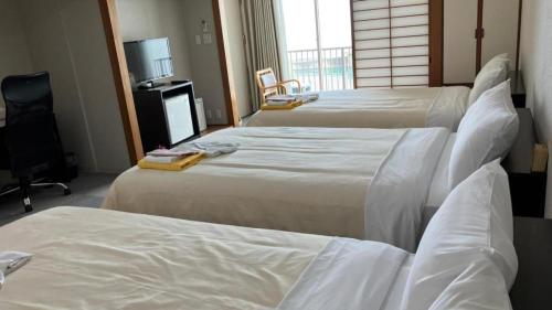 a hotel room with three beds with white sheets at Hamakan Hotel in Unzen