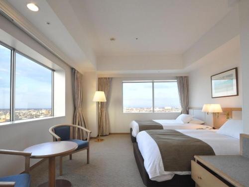 a hotel room with two beds and large windows at Grand Hotel New Oji in Tomakomai