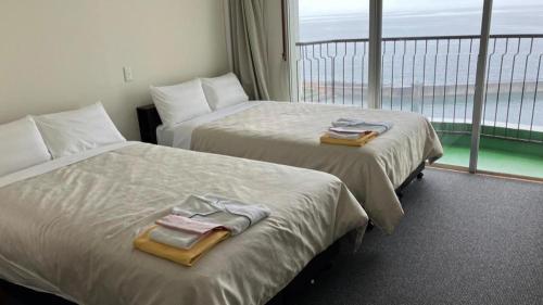 two beds in a hotel room with a balcony at Hamakan Hotel in Unzen