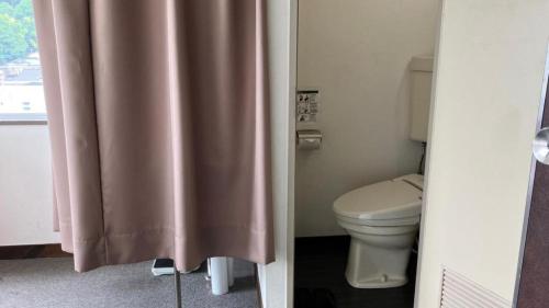 a bathroom with a toilet and a shower curtain at Hamakan Hotel in Unzen