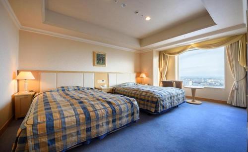 a hotel room with two beds and a large window at Grand Hotel New Oji in Tomakomai