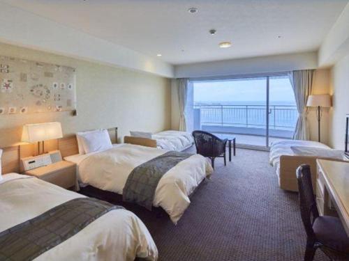 a hotel room with four beds and a balcony at Hotel Harvest Nankitanabe in Tanabe