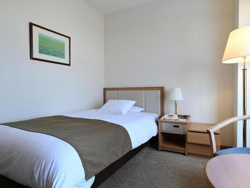a bedroom with a bed and a table and a chair at Grand Hotel New Oji in Tomakomai