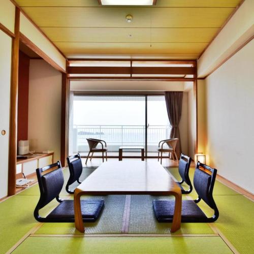 a room with a table and chairs and a large window at Hotel Harvest Nankitanabe in Tanabe
