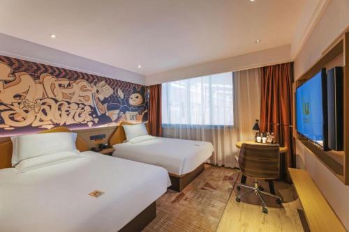 a hotel room with two beds and a flat screen tv at IU Hotel Wujiang Huadong Business City Tongli in Suzhou