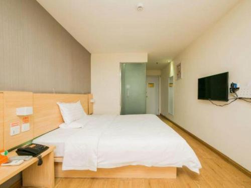 a bedroom with a white bed and a desk and a television at 7 Days Inn Changchun Zhengyang Street Changchun Park Branch in Changchun