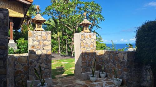 a stone fence with potted plants on it at Frangipani Inn & Restaurant in Seraya