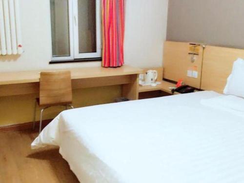 a bedroom with a bed and a desk and a window at 7 Days Inn Changchun Zhengyang Street Changchun Park Branch in Changchun