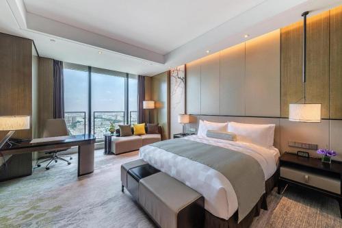 a bedroom with a large bed and a desk and a desk at Golden Eagle Summit Hotel Kunshan in Suzhou