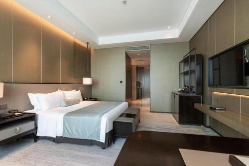 a hotel room with a bed and a television at Golden Eagle Summit Hotel Kunshan in Suzhou