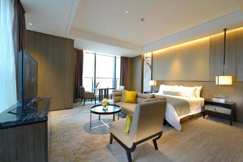 a hotel room with a bed and a couch at Golden Eagle Summit Hotel Kunshan in Suzhou