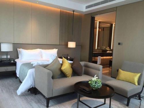 a bedroom with a bed and a couch and a table at Golden Eagle Summit Hotel Kunshan in Suzhou