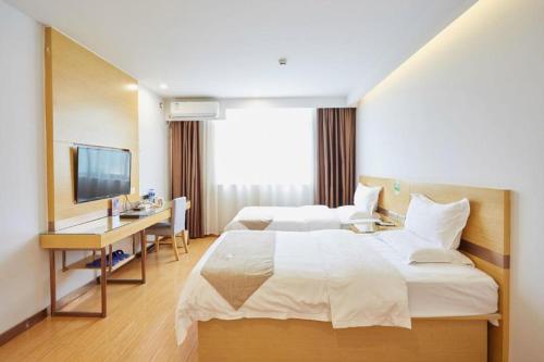 a hotel room with two beds and a desk and a television at GreenTree Inn Huayin Huashan Town Huashan Scenicspot Express Hotel in Huayin
