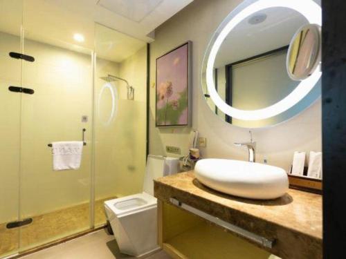 a bathroom with a sink and a toilet and a mirror at Lavande Hotels Suzhou Railway Station in Suzhou