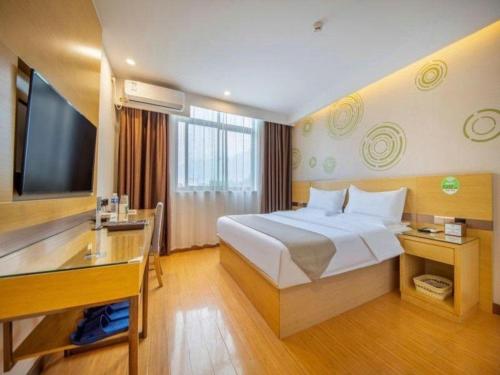 a hotel room with a bed and a desk and a television at GreenTree Inn Huayin Huashan Town Huashan Scenicspot Express Hotel in Huayin