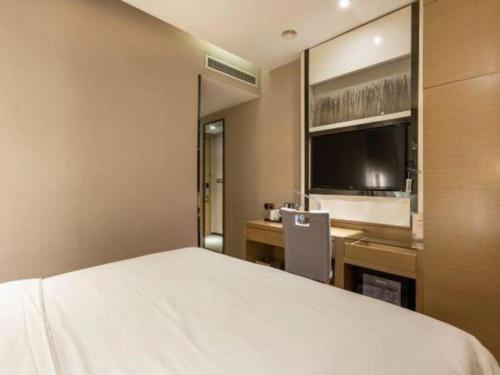 a bedroom with a large bed and a flat screen tv at Lavande Hotels Suzhou Railway Station in Suzhou