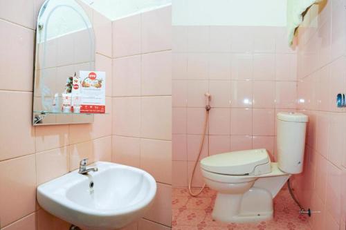 a pink bathroom with a sink and a toilet at OYO 236 Penginapan Rumah Hijau in Sukarami