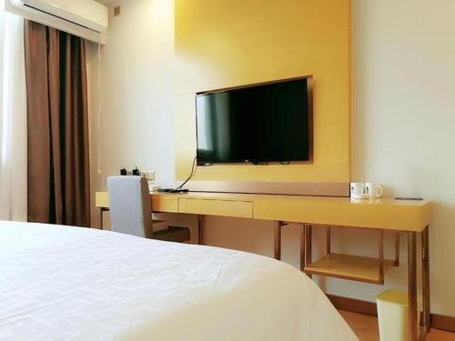 a hotel room with a desk with a flat screen tv at GreenTree Inn Huayin Huashan Town Huashan Scenicspot Express Hotel in Huayin