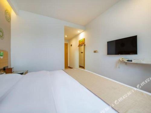 a bedroom with a large bed and a flat screen tv at GreenTree Inn Huayin Huashan Town Huashan Scenicspot Express Hotel in Huayin