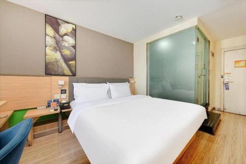 a bedroom with a large white bed and a desk at 7 Days Inn West Gate of Taiyuan University of Technology in Taiyuan