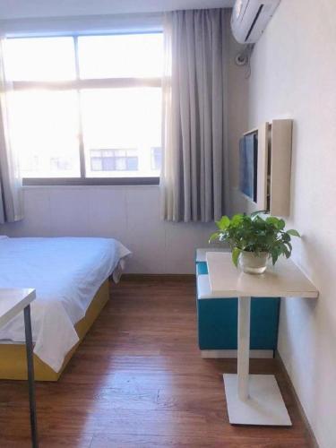 a bedroom with a bed and a table with a potted plant at 7 Days Inn·Taixing Wenchang Road in Taixing