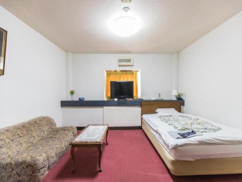 a hotel room with a bed and a couch at Tabist Joetsu Central Hotel Takada Nakamachi in Joetsu