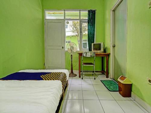 バンドンにあるSPOT ON 91325 Pondok Hijau Guest House Syariahのベッドと机と窓のある寝室
