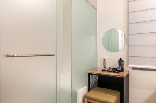 a bathroom with a mirror and a stool next to a door at Crossing Hotel in Seoul