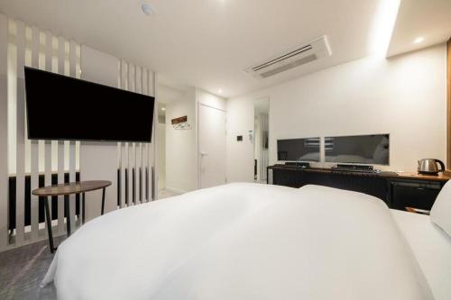 a white bedroom with a bed and a flat screen tv at Crossing Hotel in Seoul