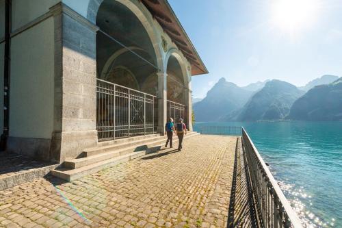 two people walking on a pier next to the water at SimpleSparks I Luzern I Andermatt I Natur I Family in Altdorf