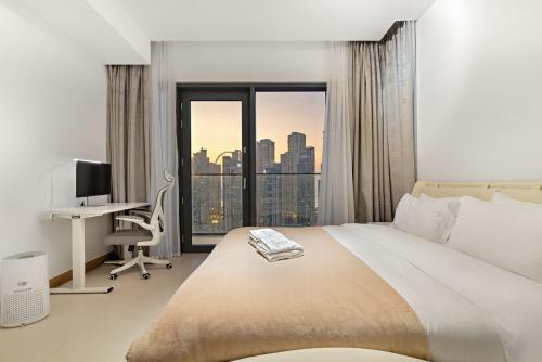 a bedroom with a bed and a desk with a computer at Panoramic Marina 1BR City Skyline Views with Balcony, Pool & Gym Access in Dubai