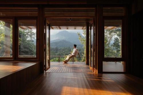 a man sitting on a balcony looking out at a mountain at Ruedufon- Private Nature Retreat in Chiang Dao in Ban Tham