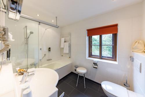 a bathroom with a tub and a sink and a toilet at Der Schlosswirt zu Anif - Biedermeierhotel und Restaurant in Anif
