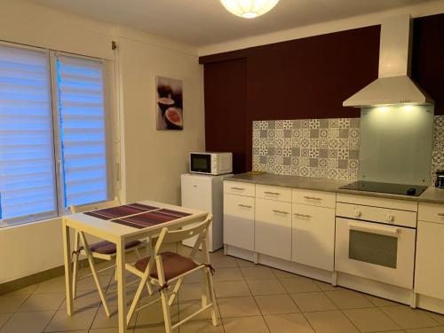 une cuisine avec des armoires blanches, une table et un micro-ondes dans l'établissement Maisonnette proche bord de Loire, à Saint-Julien-de-Concelles