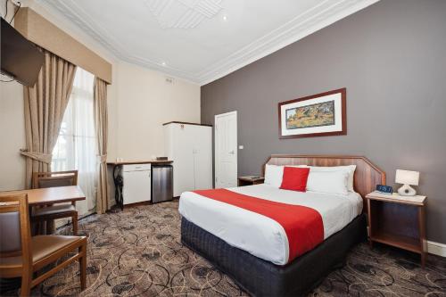 a hotel room with a large bed and a desk at Quality Hotel Bayswater in Perth