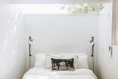 a bedroom with a white bed with two lights at Neds Nook in Beechworth