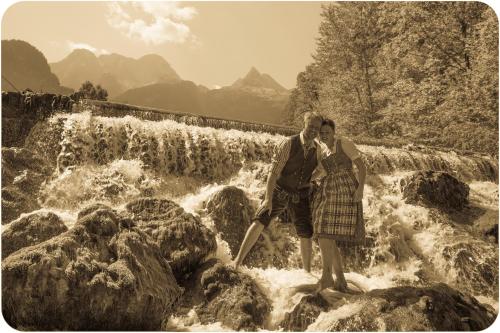 a man and woman standing on rocks in front of a waterfall at Hotel - Wirts'haus "Zum Schweizer" in Lofer